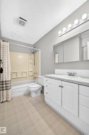 Bathroom featuring a single vanity with white cabinetry, a built-in sink, and a tiled backsplash - 