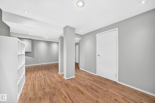Expansive room featuring wood-finish flooring, recessed ceiling lighting, light gray painted walls, and white trim - 32 Mcleod Place, Edmonton, AB 
