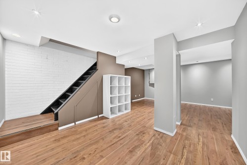 Spacious finished lower level featuring wood-finish flooring, recessed lighting, white brick-pattern wall, and neutral wall paint - 32 Mcleod Place, Edmonton, AB 