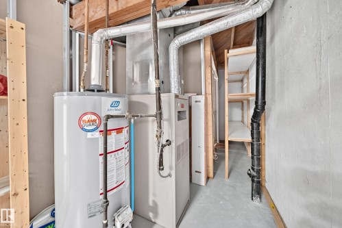 Utility area featuring a water heater, furnace, exposed ductwork, and built-in shelving units - 32 Mcleod Place, Edmonton, AB 