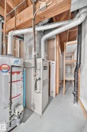 Utility area featuring a water heater, furnace, exposed wood ceiling joists, and open shelving - 