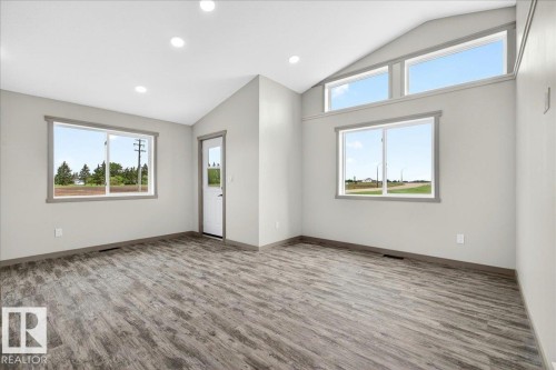 Vaulted ceiling room featuring wood-finish flooring, recessed lighting, and multiple windows - 1 Whitetail Way, Mundare, AB 