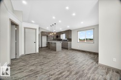 Open-concept living space featuring wood-finish flooring, recessed lighting, and a modern kitchen with a central island - 
