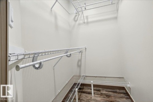 Walk-in closet featuring wood-finish flooring, white wire shelving, and an integrated hanging rod system - 1 Whitetail Way, Mundare, AB 