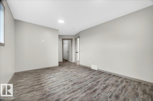Spacious room featuring wood-finish flooring, light gray walls, and recessed lighting - 1 Whitetail Way, Mundare, AB 