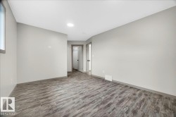 Spacious room featuring wood-finish flooring, light gray walls, and recessed lighting - 
