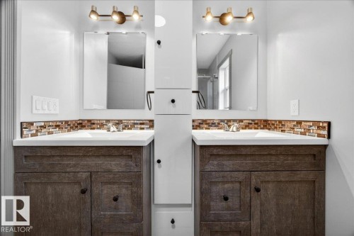 Dual vanity with wood-finish cabinetry, integrated white sinks, and a mosaic tile backsplash - 1 Whitetail Way, Mundare, AB 