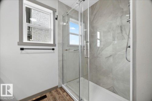 Walk-in shower with clear glass enclosure and light-toned, large-format wall tiling - 1 Whitetail Way, Mundare, AB 
