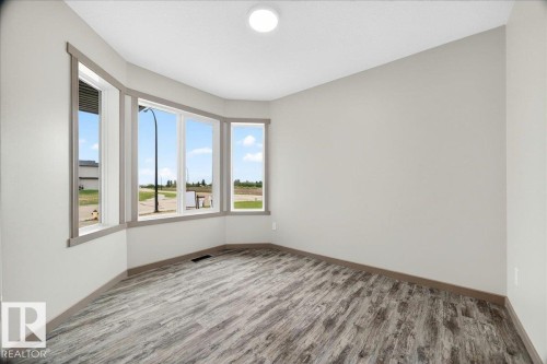 Bay window with multiple panes, wood-finish flooring, light neutral wall paint, white ceiling, and a flush mount ceiling light - 1 Whitetail Way, Mundare, AB 