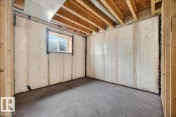 Unfinished basement with concrete flooring and exposed wood framing - 