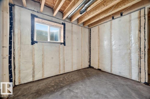 Unfinished basement space featuring exposed wooden joists, concrete flooring, a window, wall insulation, and visible ductwork - 1 Whitetail Way, Mundare, AB 