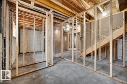 Unfinished basement featuring exposed wood framing, concrete flooring, and partial wall insulation - 
