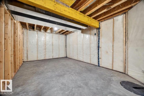 Unfinished basement featuring exposed wood framing, concrete flooring, insulated walls, open joist ceiling, and a visible support beam - 1 Whitetail Way, Mundare, AB 