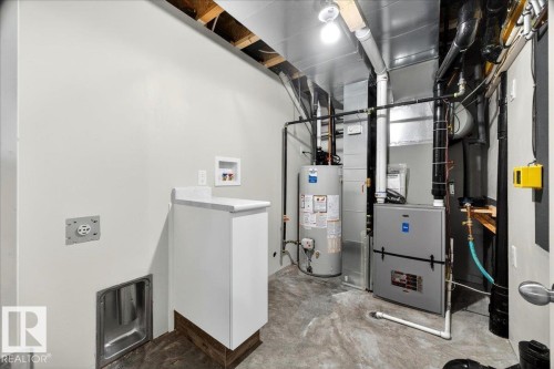 Dedicated utility space featuring a water heater, furnace system, and exposed ductwork - 1 Whitetail Way, Mundare, AB 