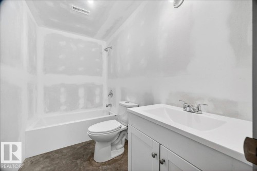 Bathroom featuring a white bathtub, toilet, and a vanity with an integrated sink - 1 Whitetail Way, Mundare, AB 