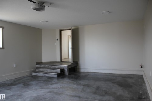 Spacious garage with painted walls, concrete flooring, and an elevated entry platform with steps - 1 Whitetail Way, Mundare, AB 