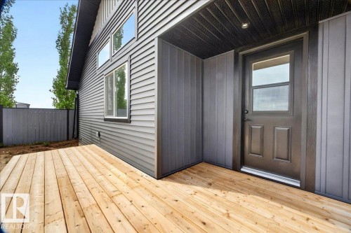 Newly constructed wood deck featuring direct access to the interior through a dark-paneled door with an integrated window - 1 Whitetail Way, Mundare, AB 