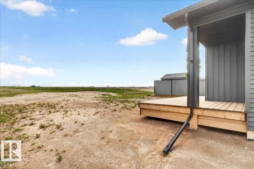 Wood-deck porch with horizontal plank flooring and a dark gray vertical panel siding exterior - 1 Whitetail Way, Mundare, AB 