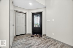 Entryway featuring a dark paneled door with decorative glass, a light paneled door, wood-finish flooring, and light gray wall paint with matching trim - 