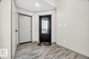 Entryway featuring a dark paneled door with decorative glass, a light paneled door, wood-finish flooring, and light gray wall paint with matching trim - 1 Whitetail Way, Mundare, AB 