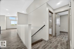 Upper-level hallway featuring wood-finish flooring, recessed lighting, and modern interior doors - 