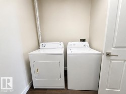 Dedicated laundry area with a white top-load washing machine and white front-load dryer - 