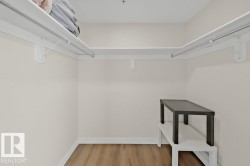 Walk-in closet featuring light wood-finish flooring, neutral wall paint, white trim, and built-in white shelving with integrated hanging rods - 