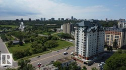 High-rise residential building featuring multiple balconies, a distinctive peaked roofline, and a light-colored exterior - 