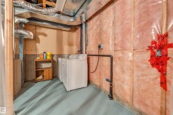 Basement utility area featuring two white appliances, exposed ductwork, and insulated walls - 