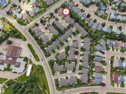 Aerial perspective showcasing a residential neighborhood with diverse housing styles, mature trees, and structured roadways - 