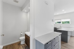 Powder room featuring wood-finish flooring, recessed lighting, and a floating vanity with a white countertop - 