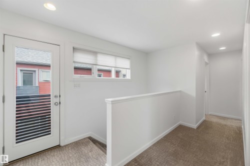 Upper-level hallway featuring a glass-paned door, transom windows with blinds, recessed lighting, and patterned carpet flooring - 1 14315 Stony Plain, Edmonton, AB 