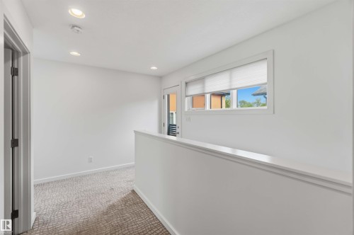 Upper-level landing featuring recessed ceiling lighting, a window with blinds, and white painted walls - 1 14315 Stony Plain, Edmonton, AB 