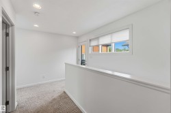 Upper-level landing featuring recessed ceiling lighting, a window with blinds, and white painted walls - 