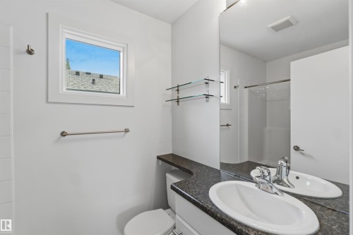Bathroom featuring a vanity with an oval undermount sink, dark speckled countertop, and a large wall-mounted mirror - 1 14315 Stony Plain, Edmonton, AB 