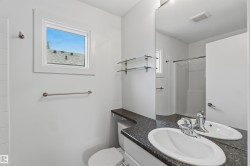 Bathroom featuring a vanity with an oval undermount sink, dark speckled countertop, and a large wall-mounted mirror - 