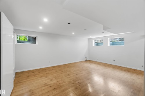 Spacious room with wood-finish flooring, white walls, and recessed lighting - 1 14315 Stony Plain, Edmonton, AB 