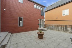 Expansive stone paver patio featuring a sliding glass door entry and two-step concrete stairs - 
