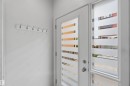 Entryway featuring a white door with frosted horizontal glass panels, a matching sidelight, and a white coat rack with six silver hooks - 1 14315 Stony Plain, Edmonton, AB 
