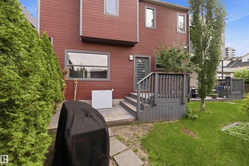 Rear exterior featuring red siding, multiple windows, and a multi-level wooden deck - 1 14315 Stony Plain, Edmonton, AB 