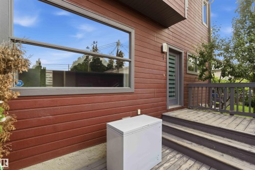 Exterior featuring horizontal wood siding, a multi-pane glass door, and a wood deck with steps and a railing - 1 14315 Stony Plain, Edmonton, AB 