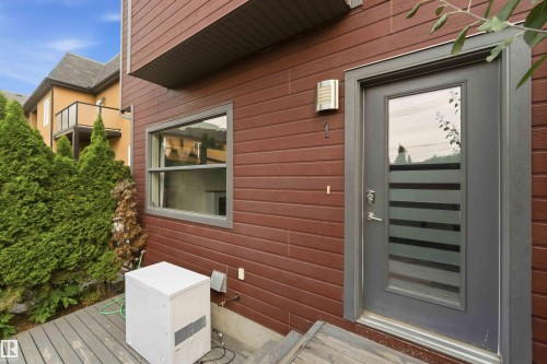 Modern exterior featuring rich wood-look siding and a contemporary gray entry door with frosted glass accents - 1 14315 Stony Plain, Edmonton, AB 