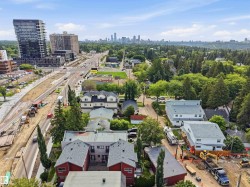 Urban landscape featuring a distant city skyline, mature treeline, high-rise buildings, and residential properties - 