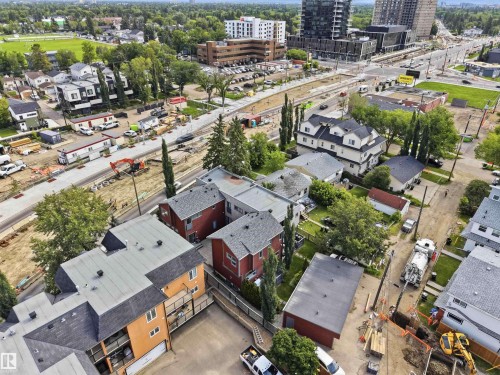 Aerial perspective showcasing a mixed residential and commercial area with multiple properties featuring varying architectural styles and rooflines - 1 14315 Stony Plain, Edmonton, AB 