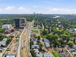 Expansive urban landscape featuring a distant city skyline, a prominent river, and a mix of residential and commercial structures - 