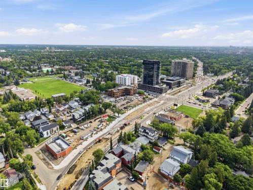 Expansive aerial perspective showcasing a mixed-use urban landscape featuring residential properties, commercial buildings, and abundant green spaces - 1 14315 Stony Plain, Edmonton, AB 