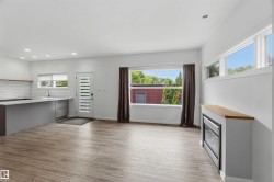 Open-concept living space featuring wood-finish flooring, a modern kitchen island with an undermount sink, a subway tile backsplash, and recessed lighting - 