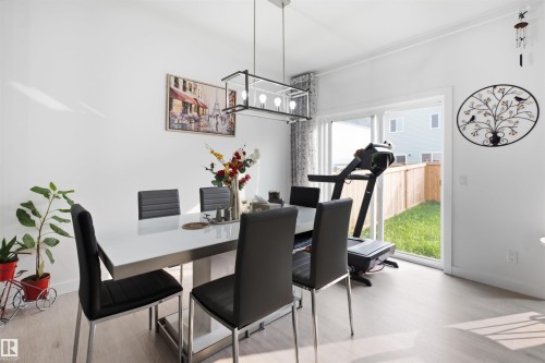 Dining area featuring light wood-finish flooring, white walls, and a contemporary linear chandelier - 2508 193 Street, Edmonton, AB 