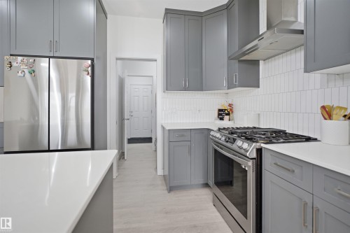 Contemporary kitchen featuring grey cabinetry, white countertops, stainless steel appliances, a gas range with matching hood, and vertical subway tile backsplash - 2508 193 Street, Edmonton, AB 