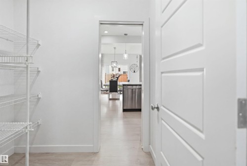 Integrated pantry shelving system with white wire racks, light-toned flooring, and a solid interior door with panel detailing - 2508 193 Street, Edmonton, AB 